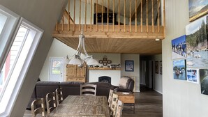 Un espace de vie de style loft comprenant un coin repas, un plafond en bois et un balcon.