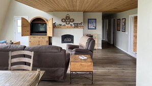 Un salon avec une cheminée, un plafond en bois et un téléviseur.
