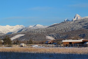 Eine Berglandschaft mit schneebedeckten Gipfeln und einer Holzhütte mit einem Metalldach.