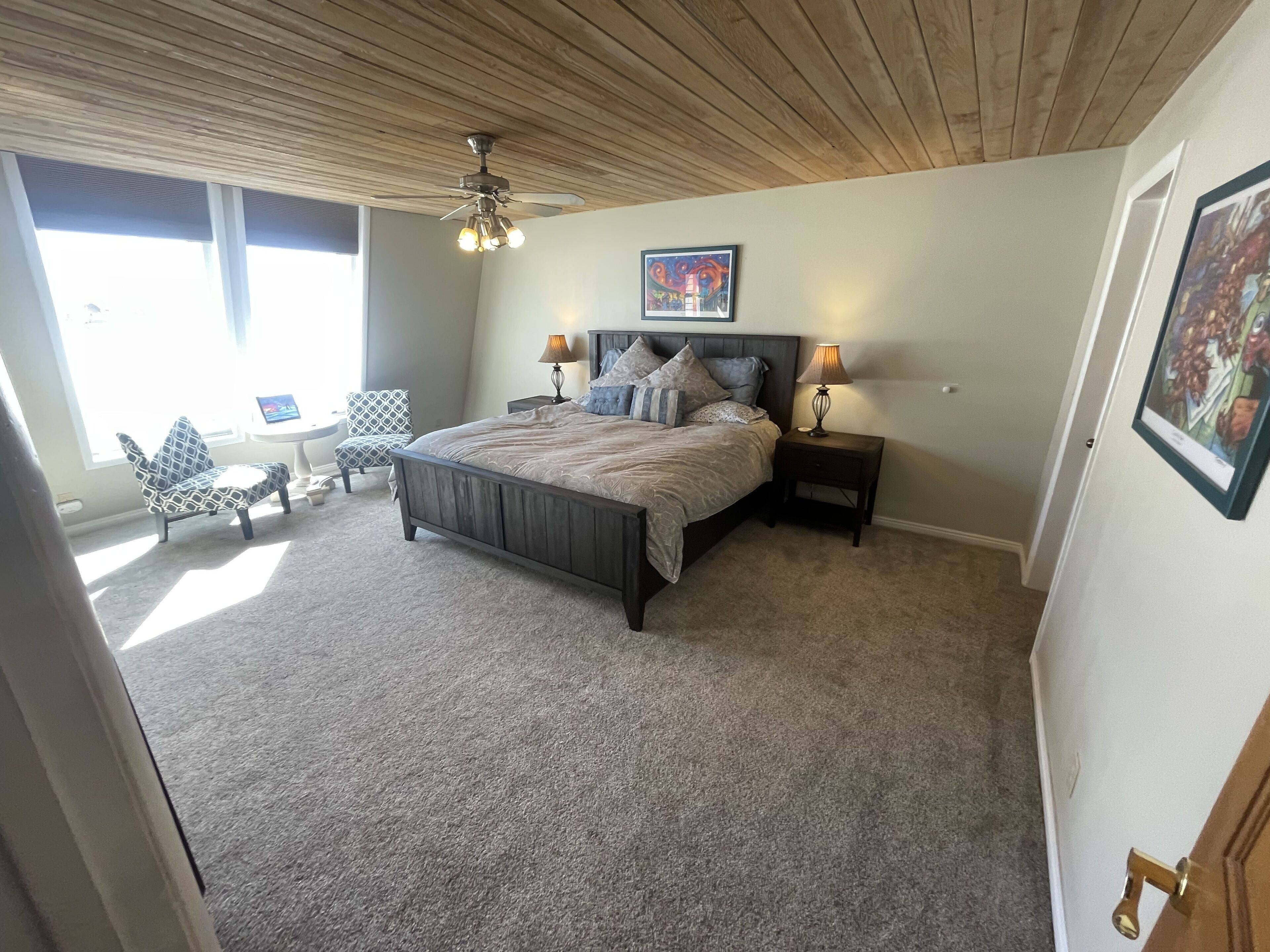 A bedroom with a bed, two bedside tables, a ceiling fan, and a window.