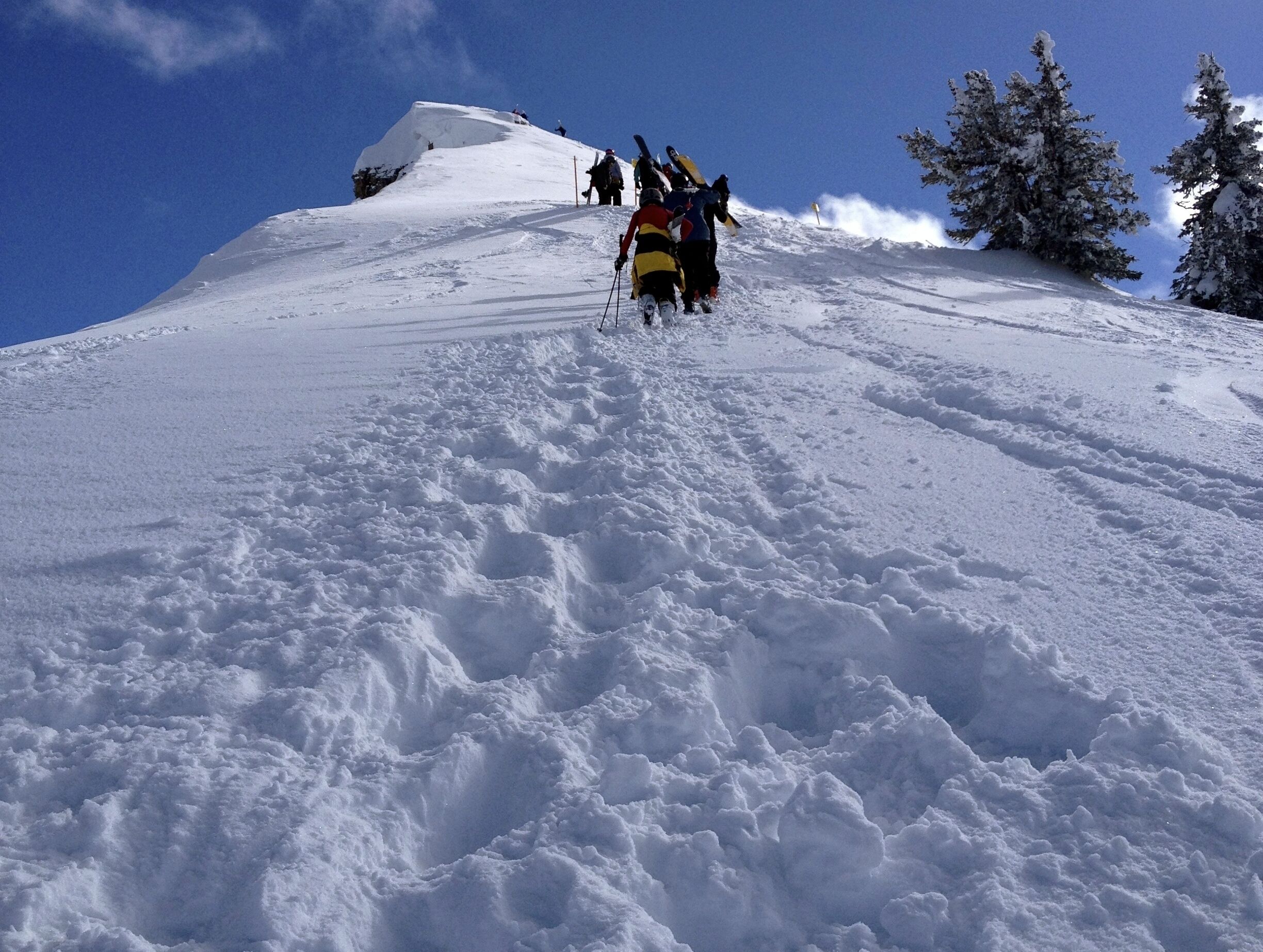 A snowy mountain slope with skiers descending.