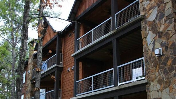 A multi-story building with stone and wood exterior, balconies, and outdoor seating.