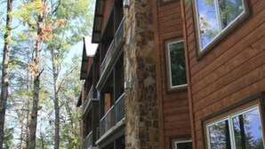 A multi-story lodge with stone and wood exterior, large windows, and a well-maintained lawn.