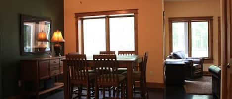 A dining area with a table and chairs, a ceiling fan, and windows.