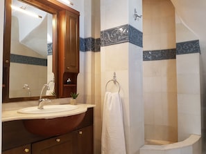 A bathroom with a wooden vanity, a sink, a mirror, and a towel rack. - Paros Holiday Villa Alyki (Paros)