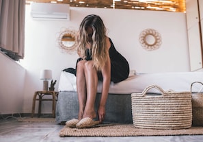 A room with a bed, a wicker basket, and a small stool. - Paros Holiday Villa Alyki (Paros)