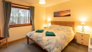 A bedroom with a bed, two bedside tables with lamps, a window with curtains, and a painting on the wall. - Pet-friendly holiday home in the quiet hamlet of Drumguish (Kingussie)