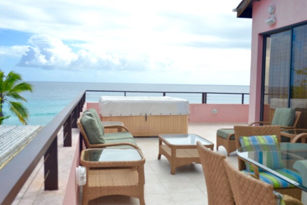 A balcony with wicker furniture, a glass table, and a view of the ocean. - Approved  Rooftop Penthouse St Lawrence Gap. (St Lawrence Gap)