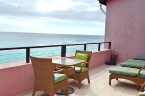 A balcony with wicker furniture, a table, and cushions, overlooking the ocean. - Approved  Rooftop Penthouse St Lawrence Gap. (St Lawrence Gap)