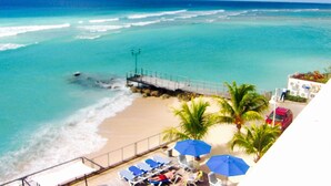 A beach view with a pier, lounge chairs, and umbrellas. - Approved  Rooftop Penthouse St Lawrence Gap. (St Lawrence Gap)