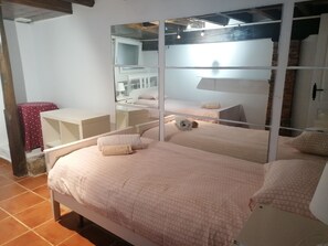 Ein Schlafzimmer mit einem großen Bett, einem Nachttisch, einem Spiegel und einem kleinen Tisch mit roter Tischdecke.