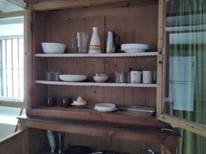 Ein Holzschrank mit Regalen, der verschiedene Küchenutensilien beherbergt.