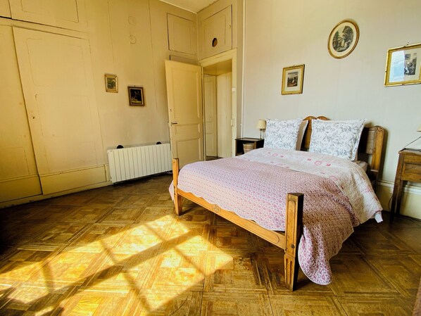 A bedroom with a wooden bed, a radiator, and a door. - Château des Tours, panoramic views, the charm of a large family home. (Ayse)