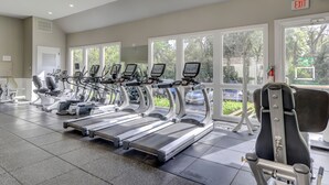 Un gimnasio con cintas de correr, elípticas y una silla.