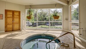Una habitación con un ventanal grande, una puerta de madera y una piscina pequeña en el interior.