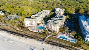 Vista aérea de un complejo turístico con varias construcciones, una piscina y una zona de playa.