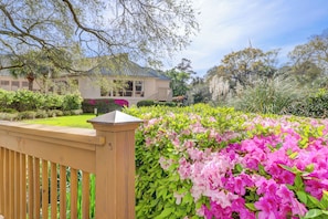 A house with a well-maintained garden featuring pink flowers and a wooden fence.