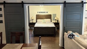 A farmhouse-style bedroom with a bed, nightstands, and a 'Welcome to the Farm' sign above the door. - Country Cottage Hideaway near Lynchburg  (Fayetteville)