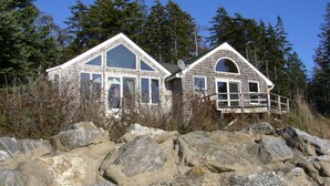 A cabin with a gabled roof, large windows, and a deck. - Private Oceanfront Cottage, Private Sand Beach -Lighthouse one mile away (Permaquid Point)