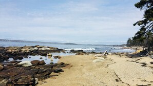 A rocky beach with a lounge chair and a staircase leading down to the water. - Private Oceanfront Cottage, Private Sand Beach -Lighthouse one mile away (Permaquid Point)