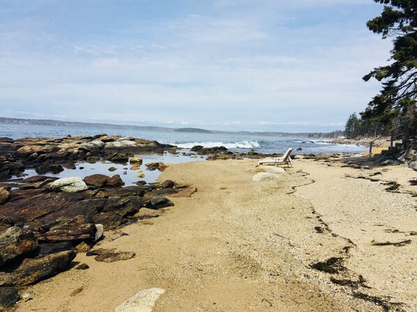 A rocky beach with a lounge chair and a staircase leading down to the water.