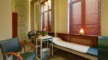 A medical examination room with a wooden bench, examination table, and a cart with medical equipment.