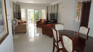 Un salón amplio con una gran mesa de comedor, asientos cómodos y un televisor.
