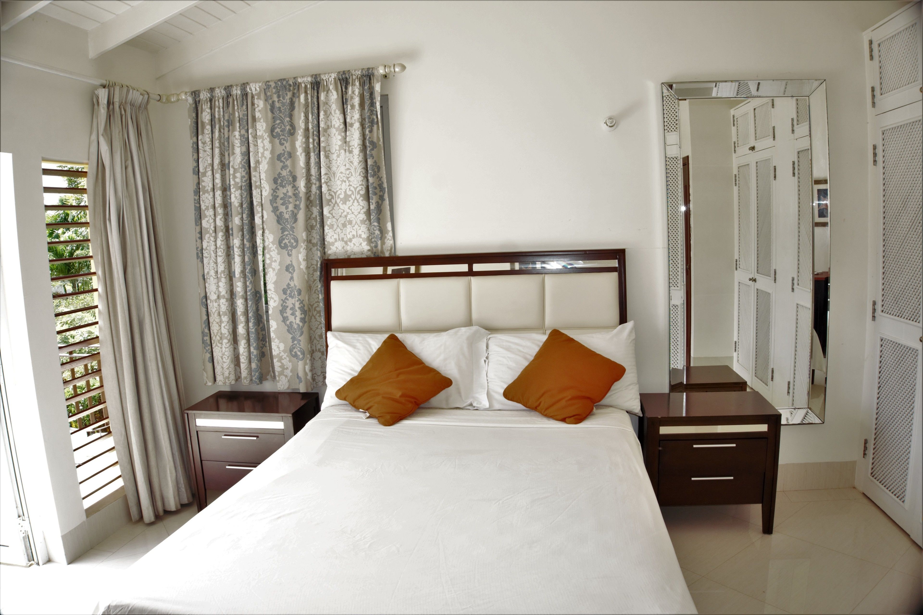 A neatly arranged bedroom with a large bed, two nightstands, and a wardrobe.