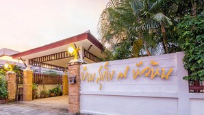 Entrada de un edificio con pared blanca y letrero dorado.