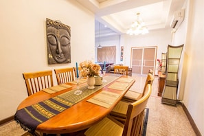 A dining area with a long wooden table, multiple chairs, a Buddha statue, and a decorative wall piece. - Baan Sukko Huahin (Hua Hin)