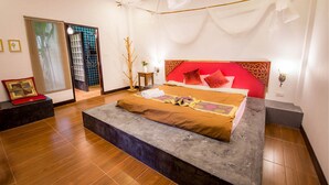 Un dormitorio moderno con una cama grande, una mesita auxiliar pequeña y una ventana con persianas.