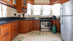 A kitchen with wooden cabinets, a stainless steel refrigerator, an oven, and a gas stove. - Sand Dollar Vacation Apartment Rental (Mangrove)