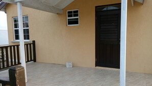 A covered outdoor area with a tiled floor, a black door, and a small window. - Sand Dollar Vacation Apartment Rental (Mangrove)