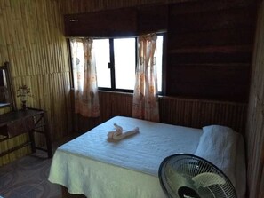 A room with a bed, a desk, and a window with curtains.