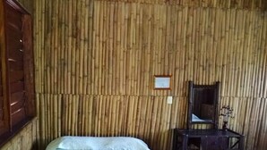 Una habitación con dos camas, una silla de madera y un reloj de pared.