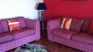 A living room with two purple checkered sofas, a glass coffee table, a lamp, and a painting on the wall. - Columbus Heights Baywatch (Ocho Rios)