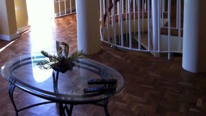 A spacious room with a glass table, a dining area with chairs, and a staircase with a railing. - Columbus Heights Baywatch (Ocho Rios)