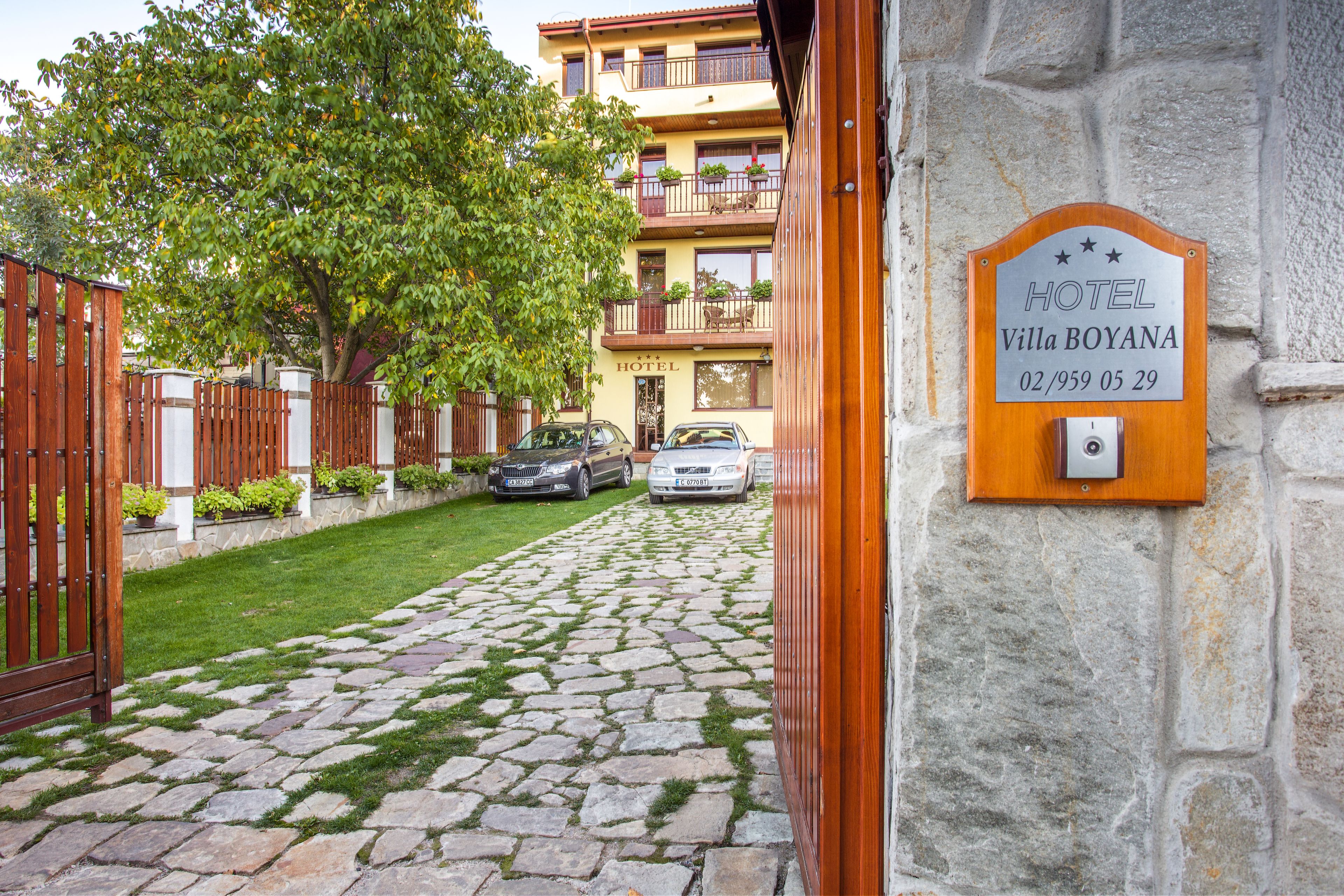 Un sendero empedrado que lleva a la entrada de un hotel, con una puerta de madera y un letrero.
