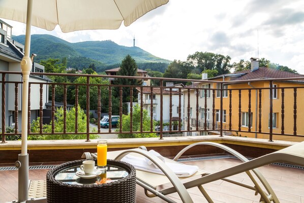 A balcony with a wicker table, a white chair, and a glass of orange juice. - Hotel Villa Boyana (Sofia)
