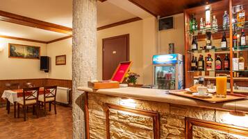 A bar area with a stone counter, a refrigerator, and a glass display case with bottles.