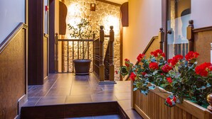 A staircase with a stone wall, wooden railing, and a potted plant with red flowers. - Hotel Villa Boyana (Sofia)