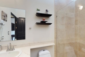 A bathroom with a white sink, a mirror, and two black shelves with decorative items.