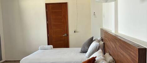 A hotel room with two beds, a wooden headboard, a white ceiling, and a window.