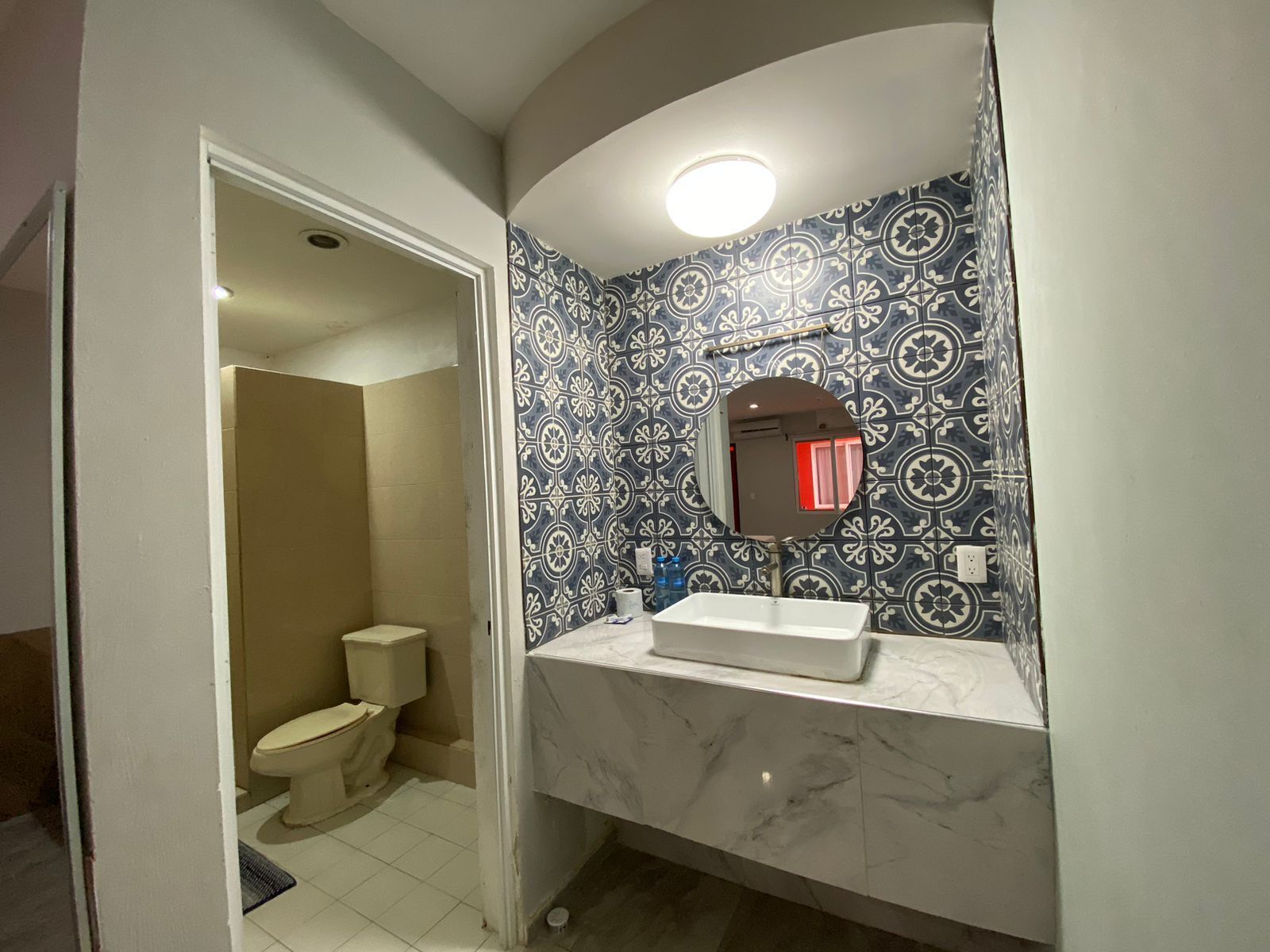 A bathroom with a toilet, sink, and mirror.
