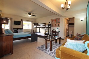 A compact hotel room with a bunk bed, a desk, a sofa, and a television. - Parham Plaza Hotel (San Pedro)