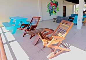A covered outdoor seating area with wooden lounge chairs and a picnic table. - Parham Plaza Hotel (San Pedro)