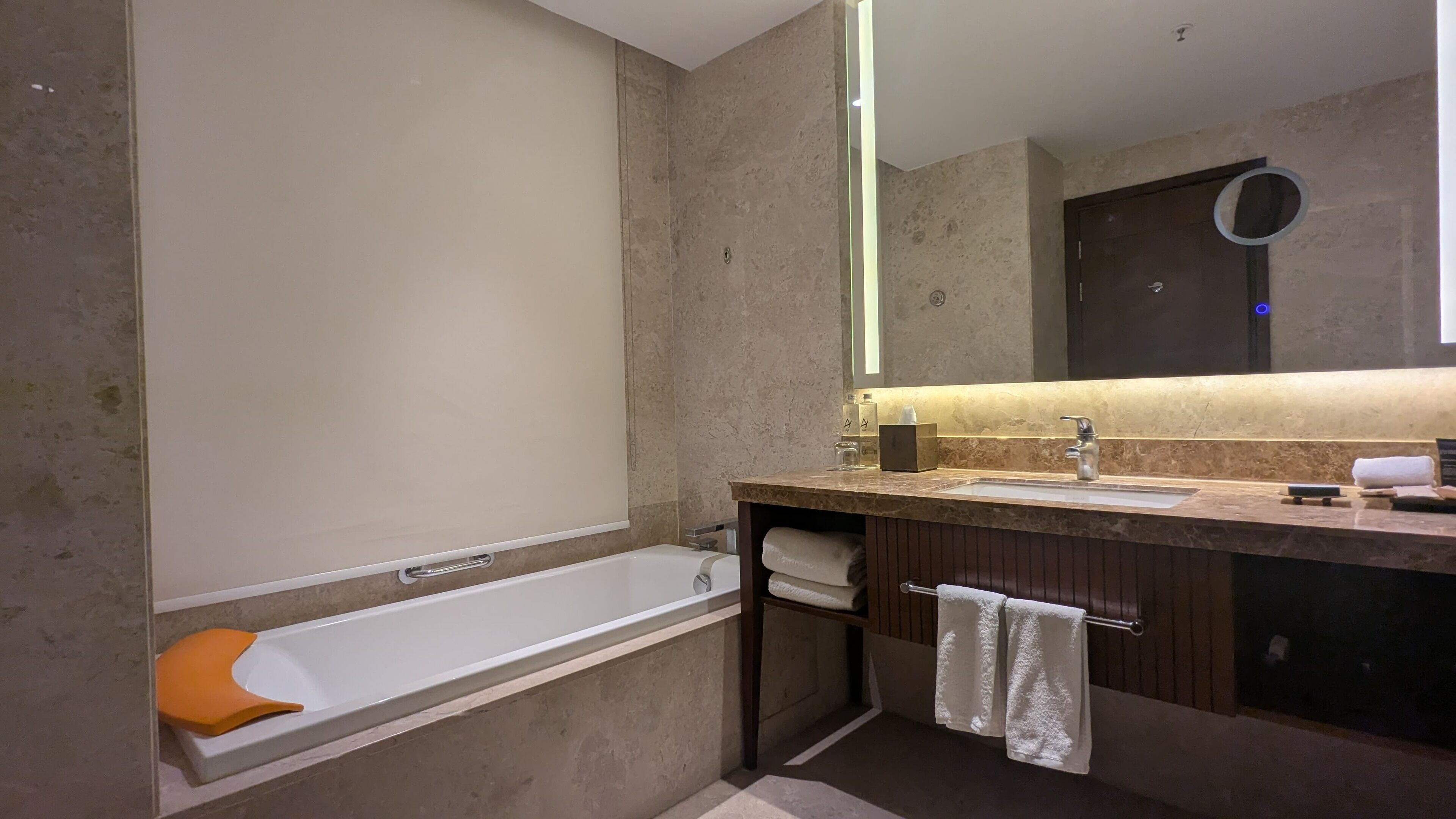 A modern bathroom with a bathtub, a vanity with a mirror, and a towel rack.