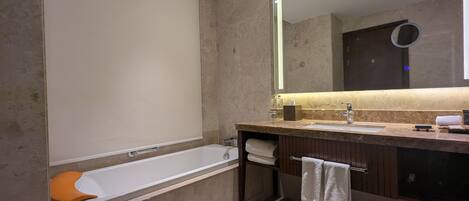 Une salle de bain moderne avec une baignoire, un meuble-lavabo avec un miroir et un porte-serviettes.