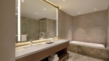A modern bathroom with a large mirror, two sinks, a bathtub, and a vanity with shelves.