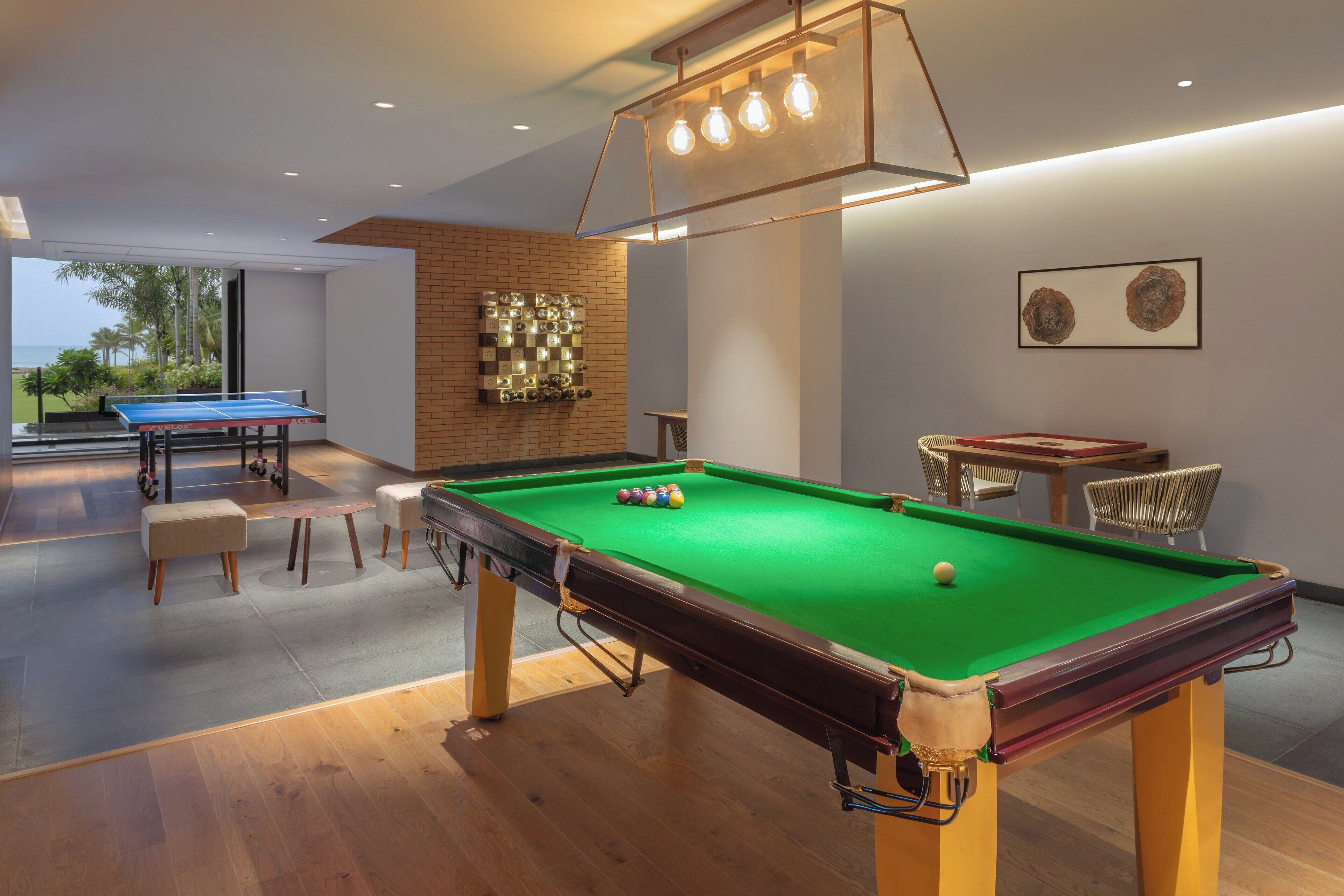 Une table de billard recouverte d’un drap vert, entourée d’un parquet et de sièges rembourrés.